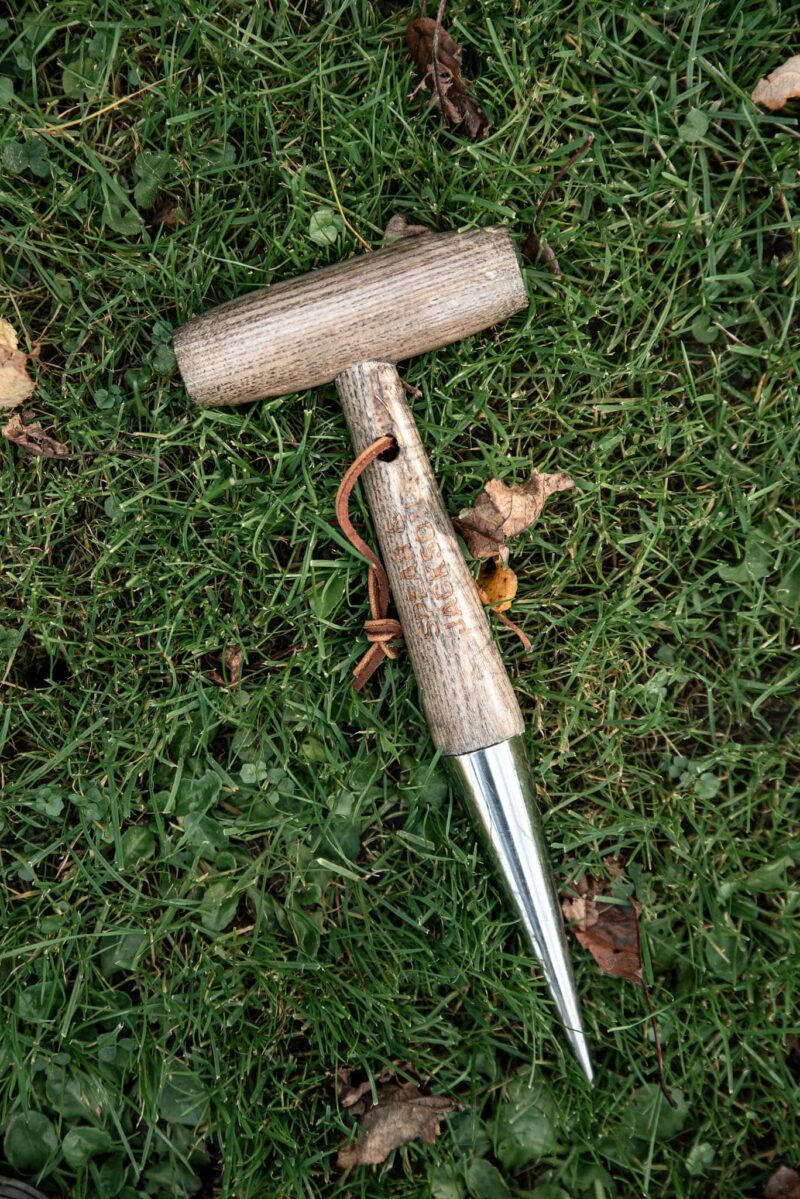 dřevěný sázecí kolík s kovovou špičkou v trávě